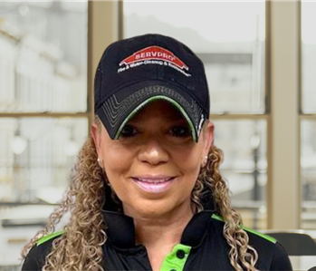 woman with long hair and a servpro shirt and hat on