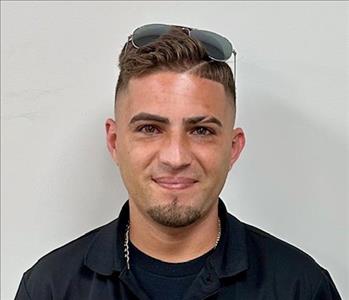 Young man with dark hair and a servpro shirt and sunglasses on his head