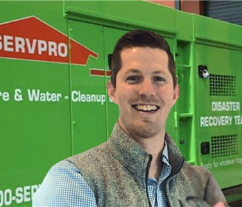 man with short brown hair smiling in front of servpro equipment