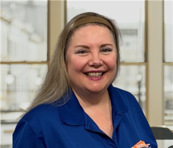 Woman with blonde hair and a blue shirt with a servpro logo on it